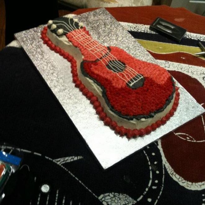 A cake carved and iced in the shape of a red electric guitar