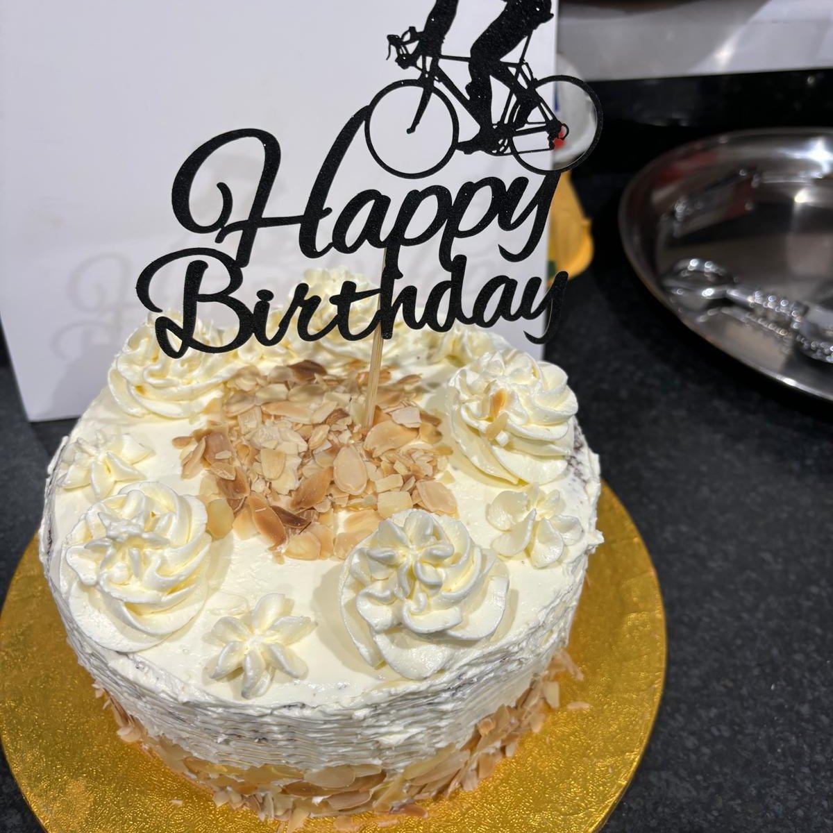 A bespoke celebration cake with piped cream and a birthday topper, baked in Medway